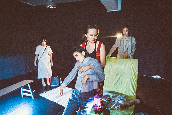 One acrtress hold another asleep actress, a third person is behind holding a mattress